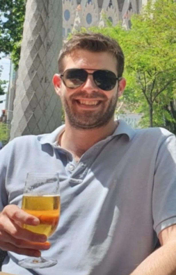 Man holding a beer in front of Sagrada Familia.