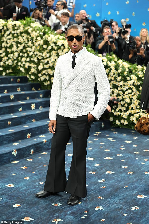 Pharrell looked stylish in black flared trousers, paired with a textured white blazer