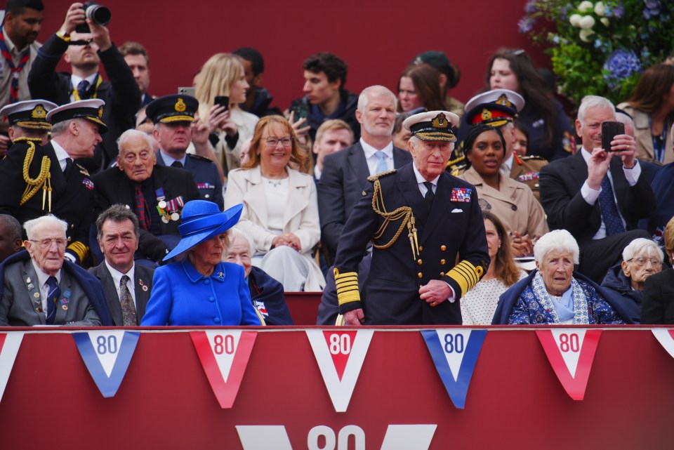 King Charles III and Queen Camilla watch a military procession at Buckingham Palace for the 80th anniversary of VE Day.