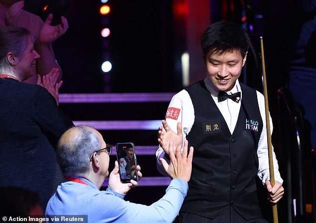 Xintong high-fives a snooker fan as he walks down the Crucible steps to head towards the famous green baize