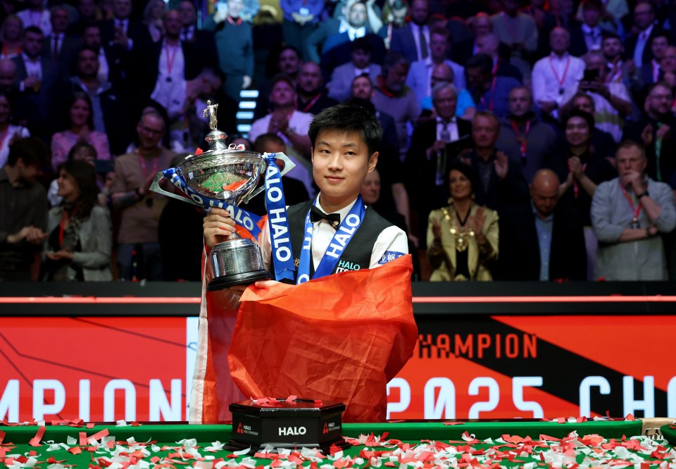 Zhao Xintong celebrates winning a snooker championship trophy.