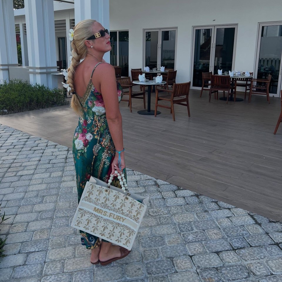 Woman in floral dress holding a tote bag.