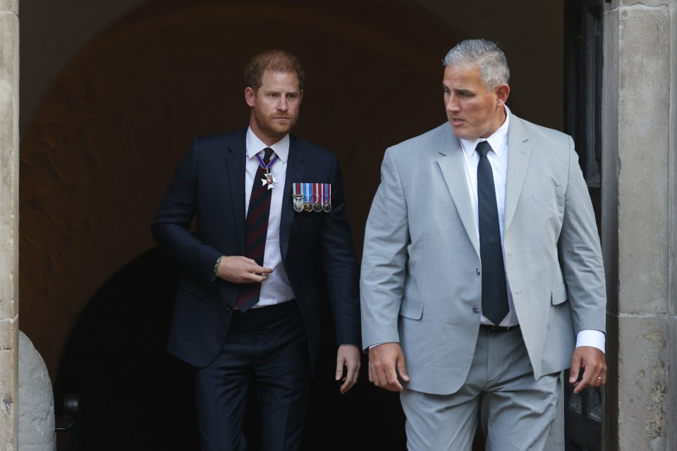 Prince Harry, Duke of Sussex, departing a building with a security guard.