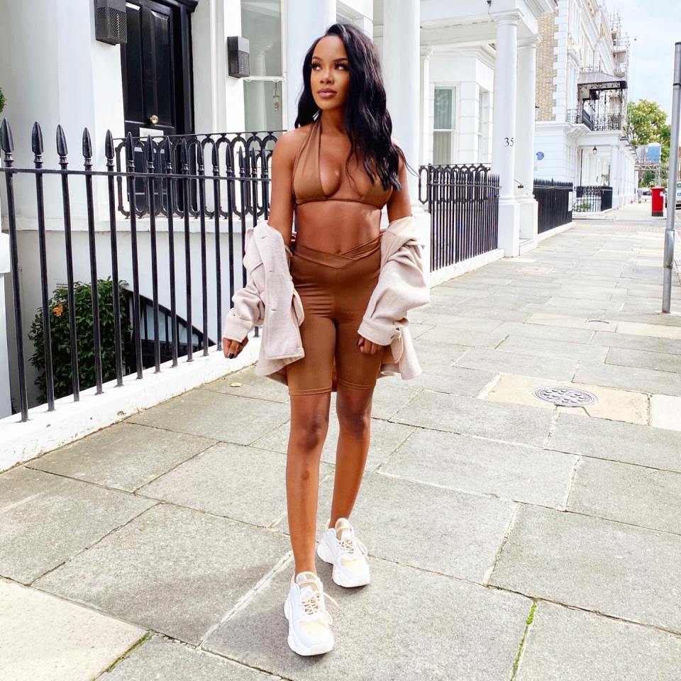 Woman in brown biker shorts and matching top walking down a street.