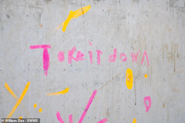 More graffiti on the unpopular wall with a message reading 'take it down'