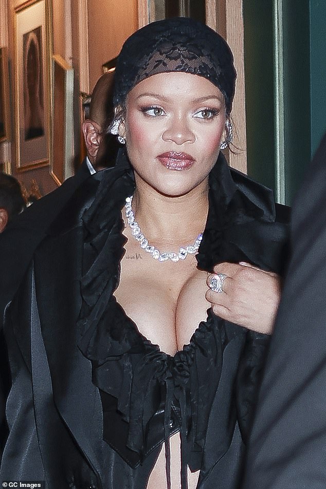 Rihanna looked great in an open silk black shirt and put on a busty display