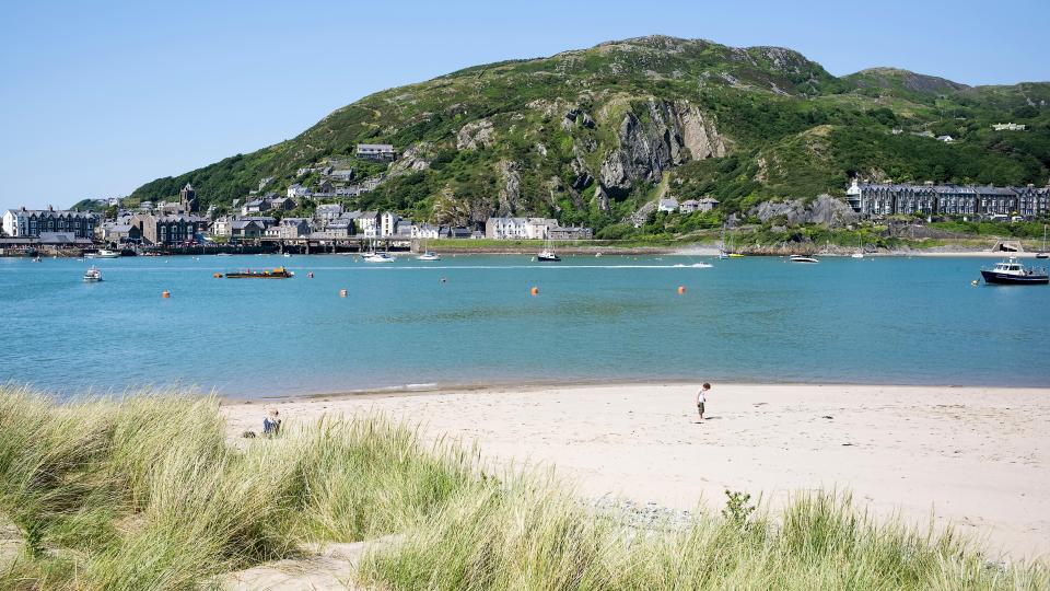 Beach at Penrhyn Point, Barmouth, with boats and a child playing on the sand.