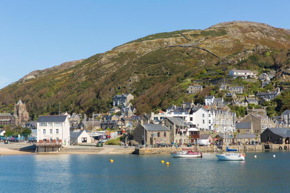 Barmouth, Wales: a coastal town nestled against a hillside, with boats in the harbor.