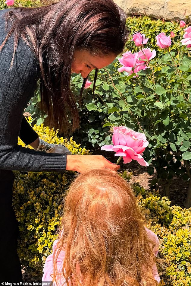 Lilibet's bright red hair is visible in this image shared by Meghan of her children enjoying summer roses in the garden