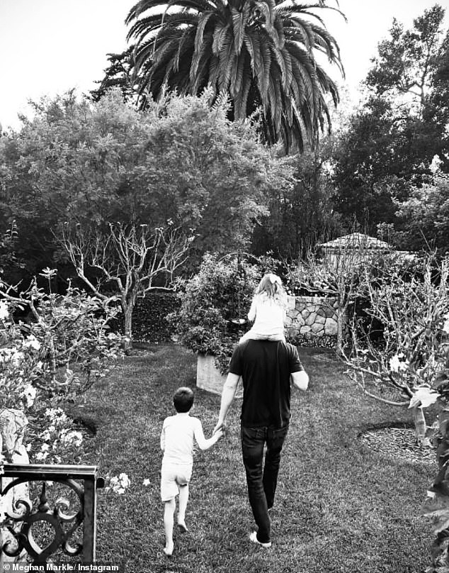 Also shared online by Meghan, the Duke clutches Archie's hand and carries Lilibet on his shoulders in this snap