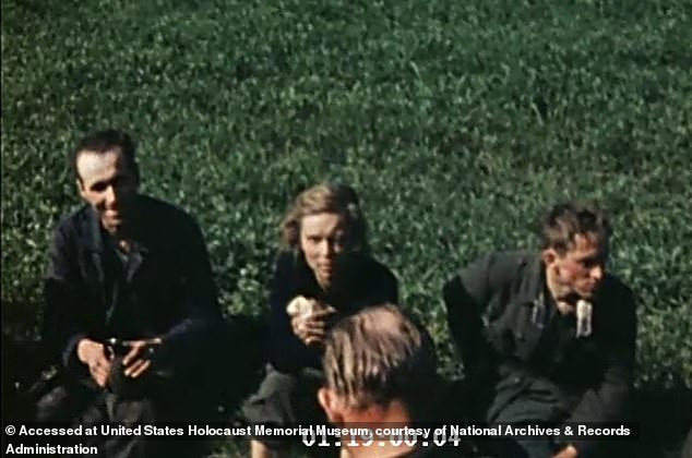 She is seen sitting with a group of male captives, holding what appears to be a cloth in her hands. Despite her battered appearance, she gives a half smile as she talks to one of the men