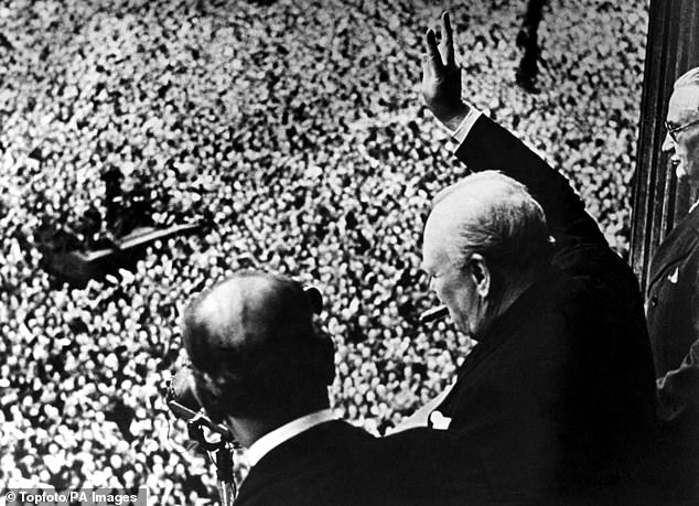 Pictured: Winston Churchill gives his famous V for Victory sign to a crowd of 50,000 full with the spirit of VE day from the balcony of the Ministry of Health