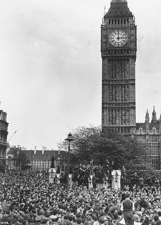 Pictured: Crowds in Westminster as Big Ben strikes 3pm, the moment Prime Minister Winston Churchill made his statement from Whitehall, declaring that the war in Europe is over