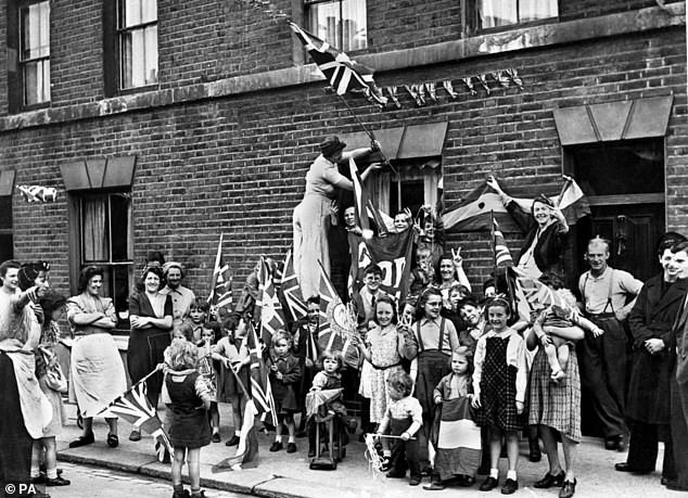 Pictured: British men, women and children celebrating 'Victory in Europe Day' in the street