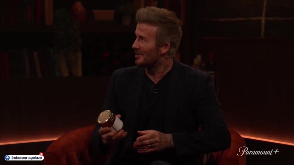 David Beckham holding a jar during an interview.