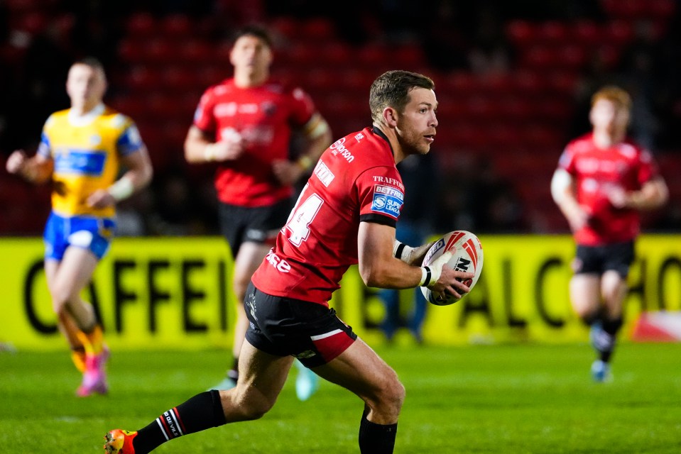 Rugby player running with the ball during a Salford Red Devils v Leeds Rhinos match.