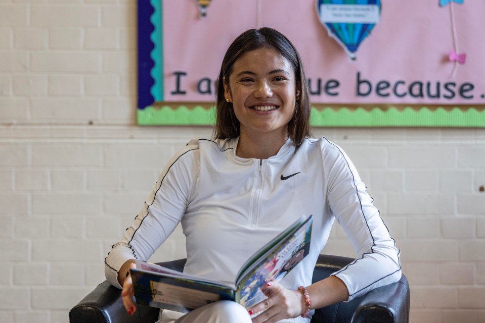 Emma Raducanu reading a book at a primary school.