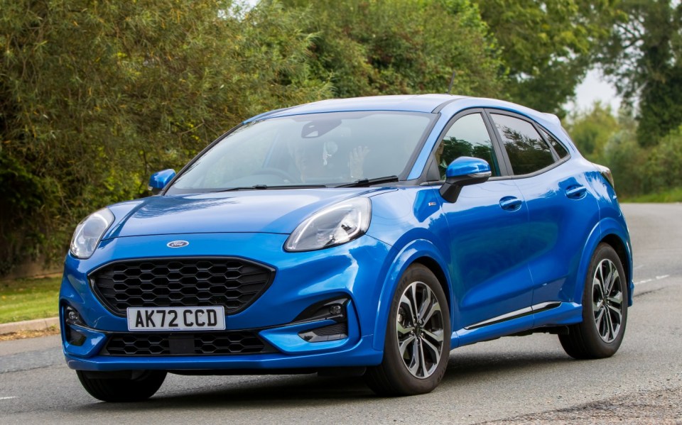 Blue Ford Puma driving on a road.
