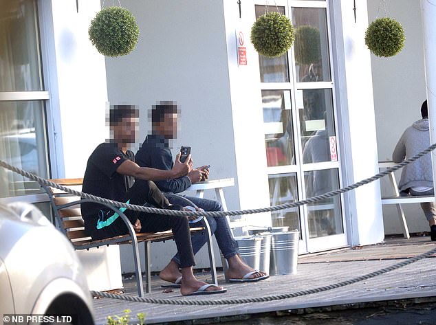 Migrants relax outside the hotel in Cheshire earlier this year