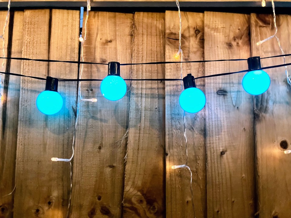 String of blue solar lights on a wooden fence.