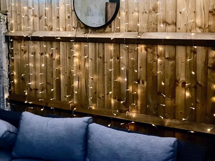 Solar-powered LED curtain lights on a wooden fence.