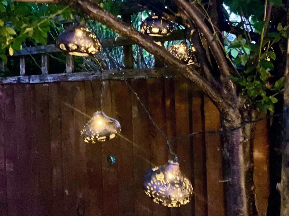 Solar-powered Moroccan lantern string lights hanging from a tree.