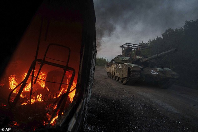 A Ukrainian tank passes by a burning car near the Russian-Ukrainian border in the Sumy region of Ukraine, Aug. 14, 2024