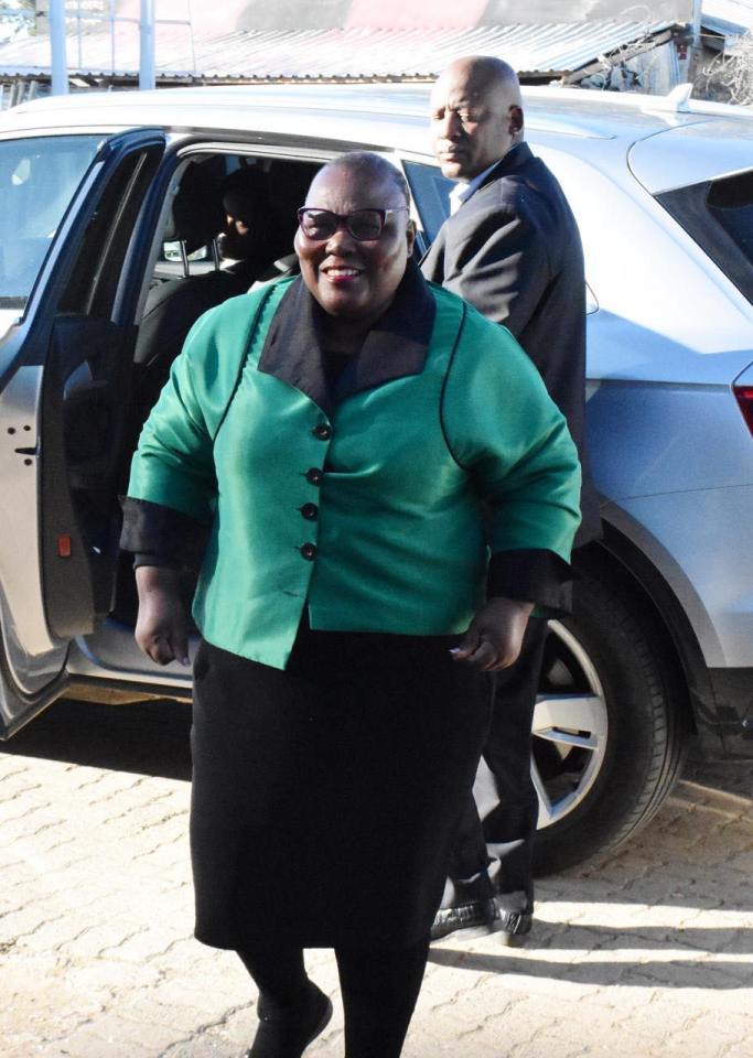 A woman in a green jacket gets out of a car with a man behind her.