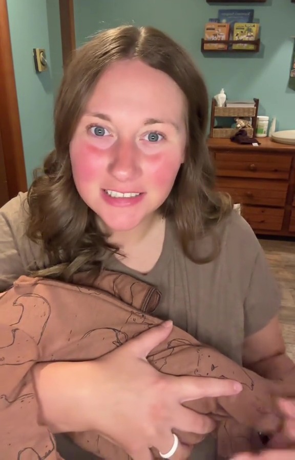 Woman holding baby in brown bear pajamas.