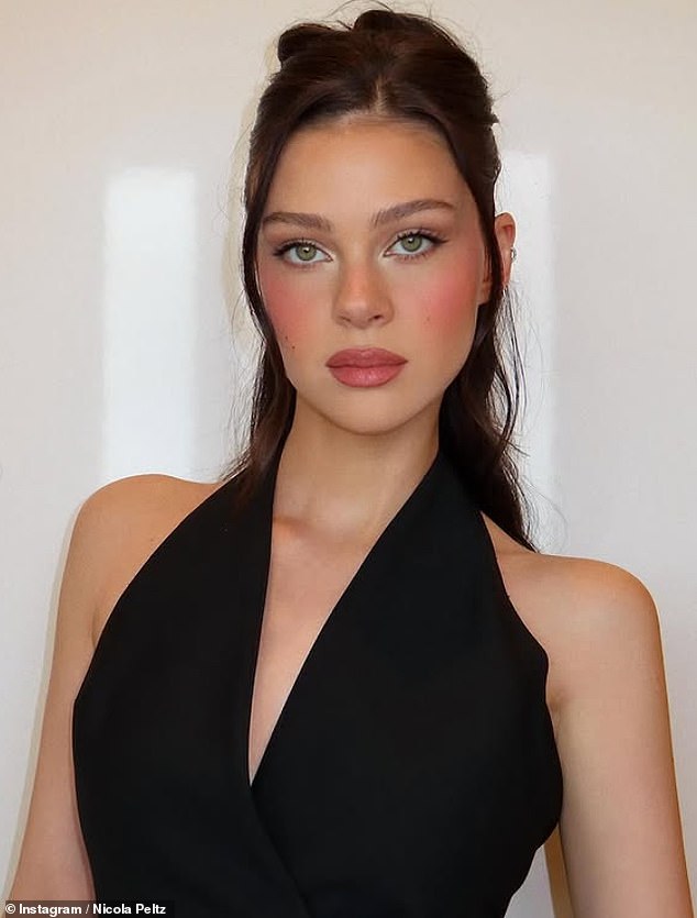 The actress posed in a plunging black waistcoat, with her brunette tresses pulled into a curled half-up, half-down style