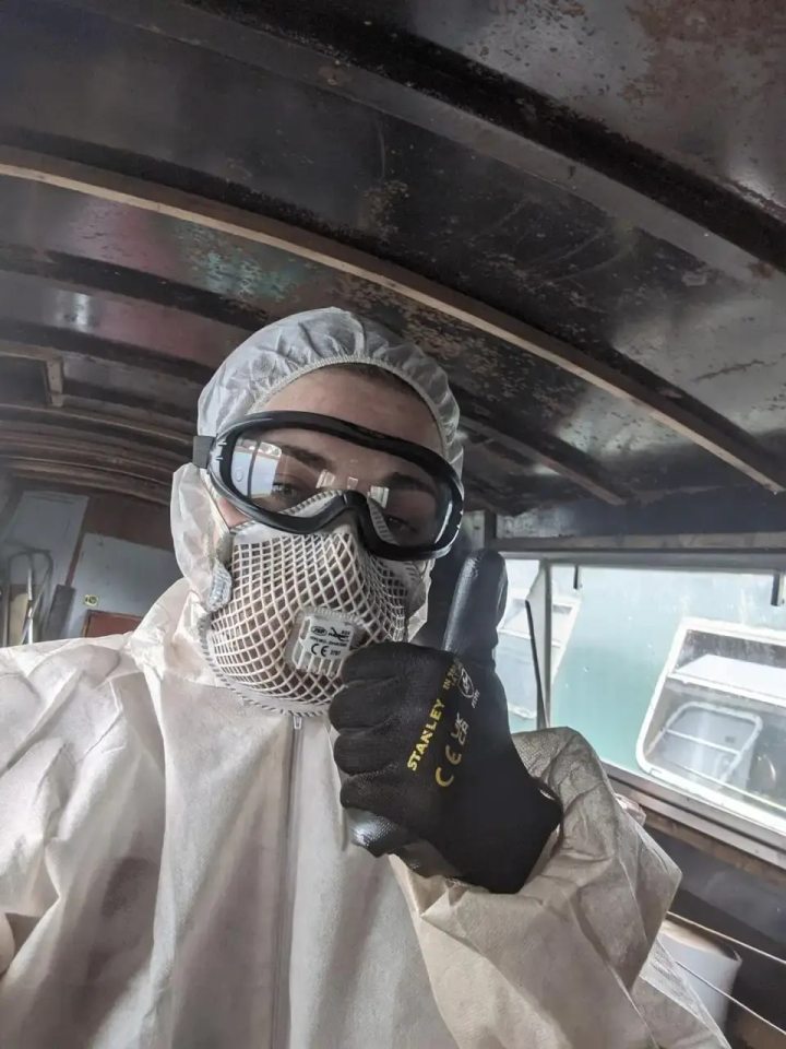 Person in protective gear giving thumbs up inside a boat.