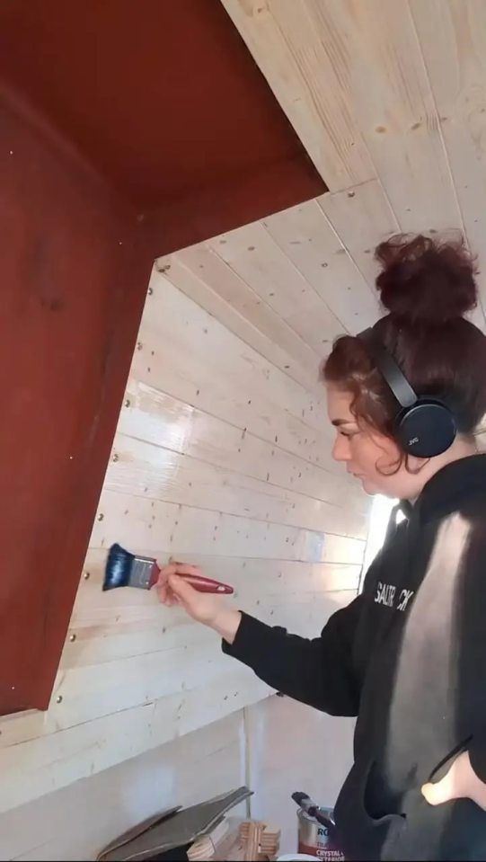 Woman painting wooden wall panels inside a narrowboat.