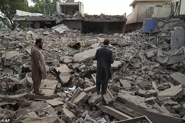 Local residents walk through the rubble of a building damaged by suspected Indian missile attack, in Muridke, a town in Pakistan's Punjab province, Wednesday, May 7, 2025