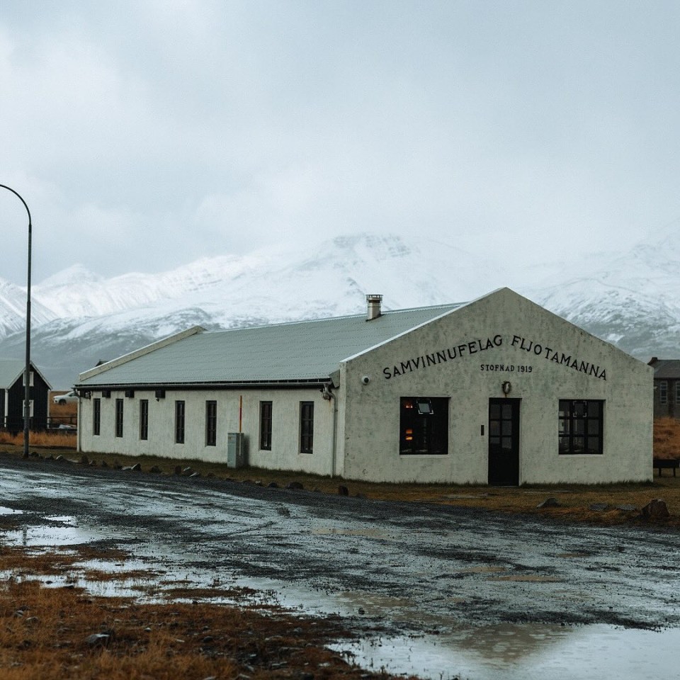 Long, low building in Iceland with snow-capped mountains in the background.