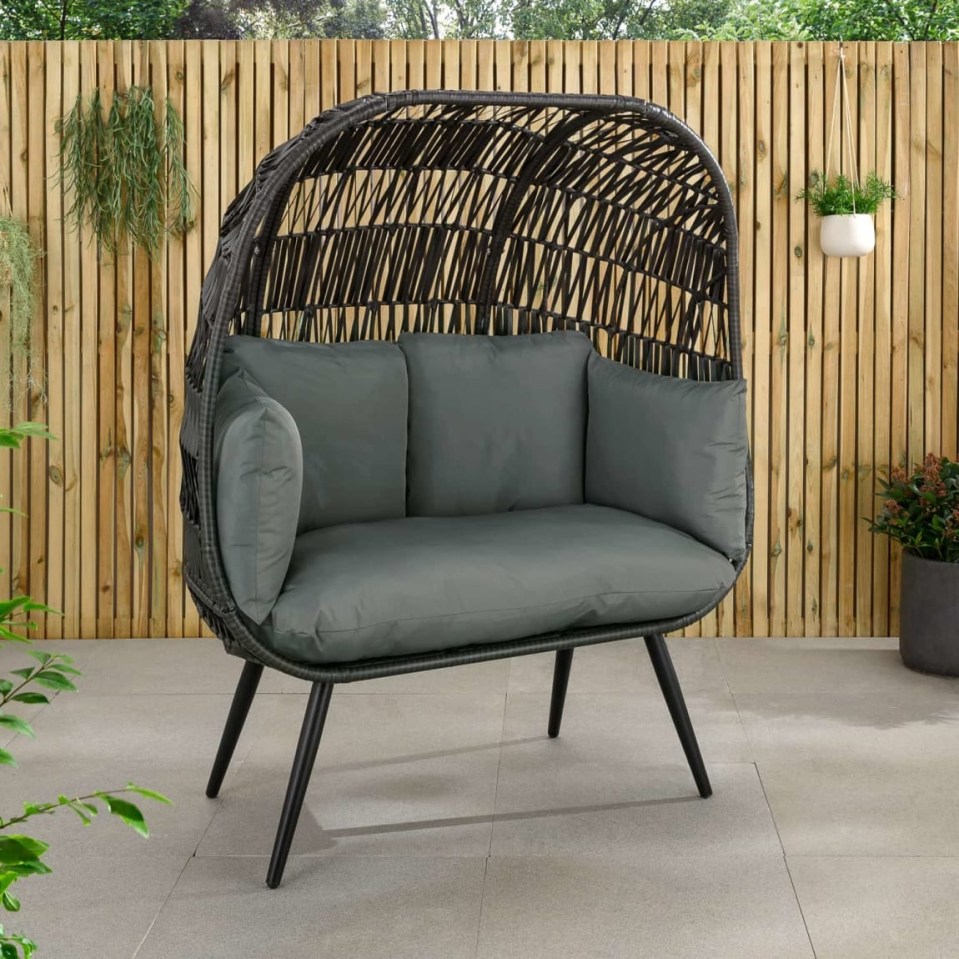 Outdoor wicker pod chair with gray cushions.