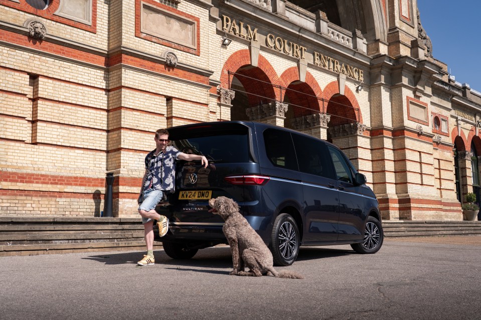 Man with dog standing by VW Multivan.