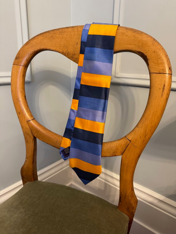 Striped tie draped over a wooden chair.
