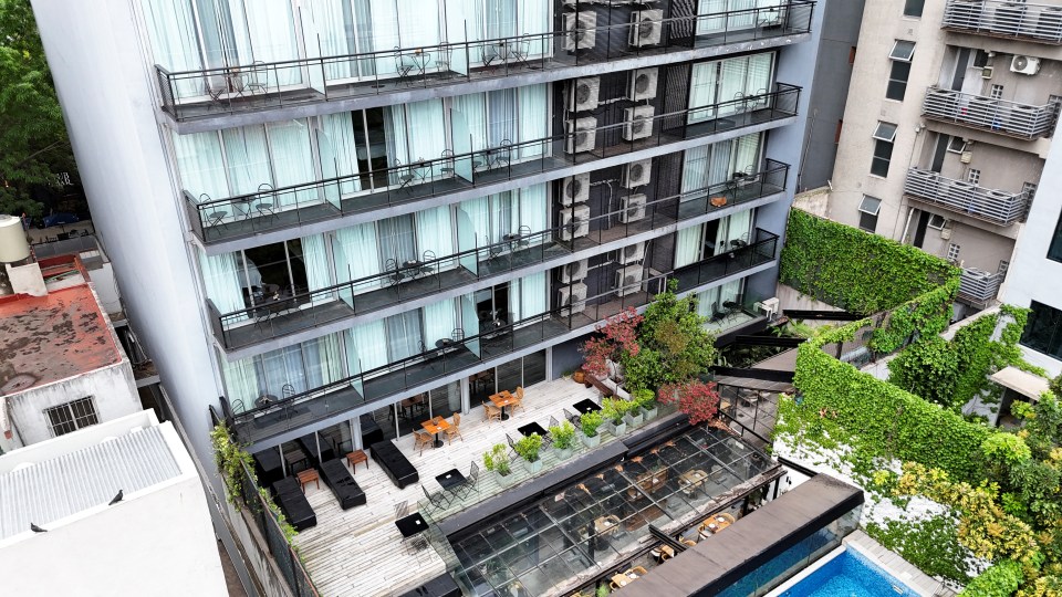 Drone view of a hotel with balconies and a rooftop patio.