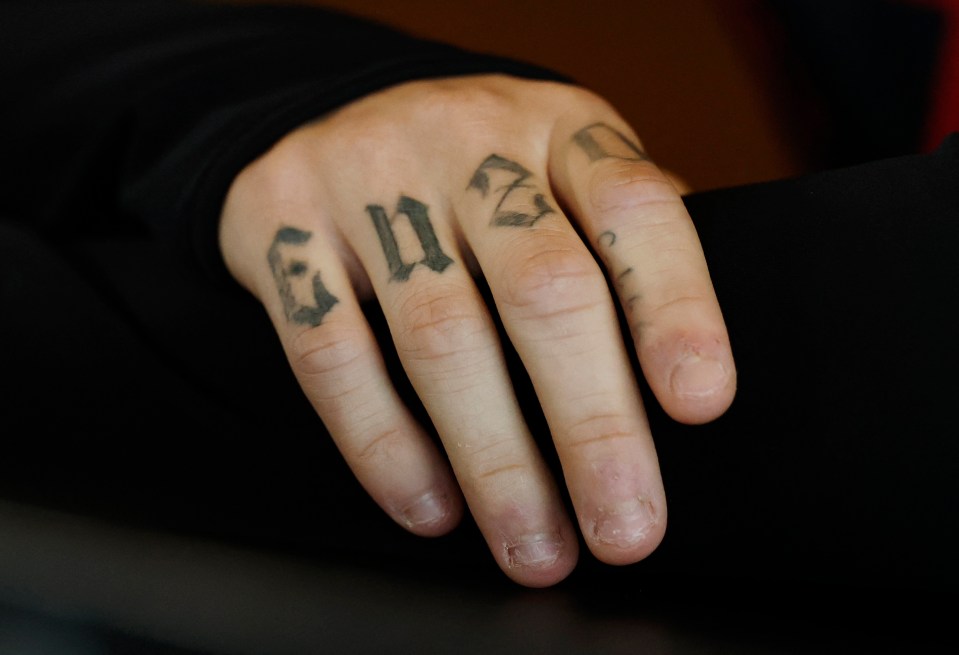 Close-up of a hand with tattoos on the fingers.