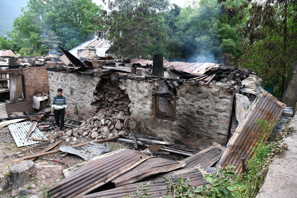 Two women stand amidst the rubble of a fire-damaged house.