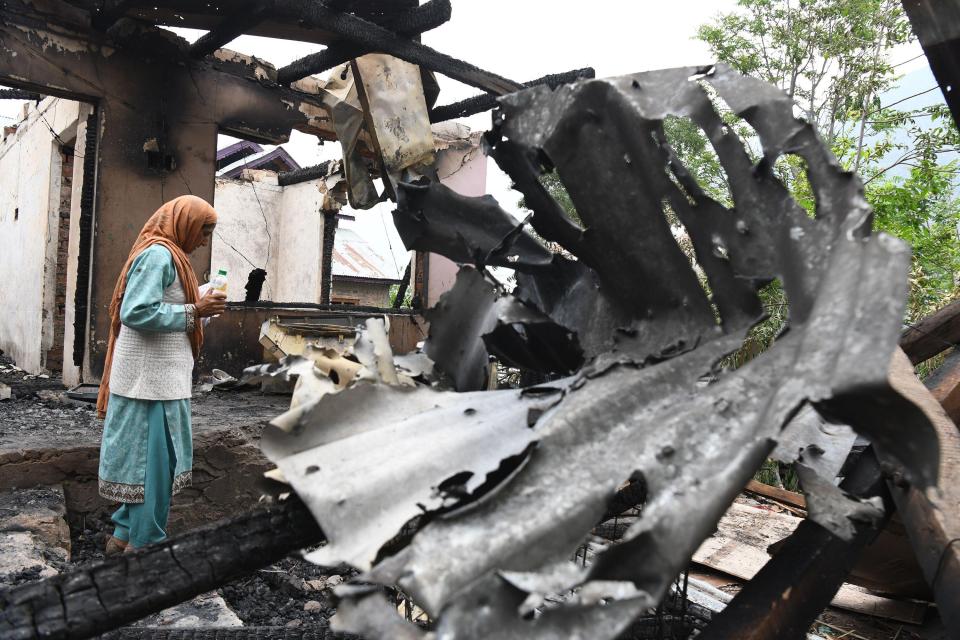 A woman stands in the remains of a fire-damaged house.