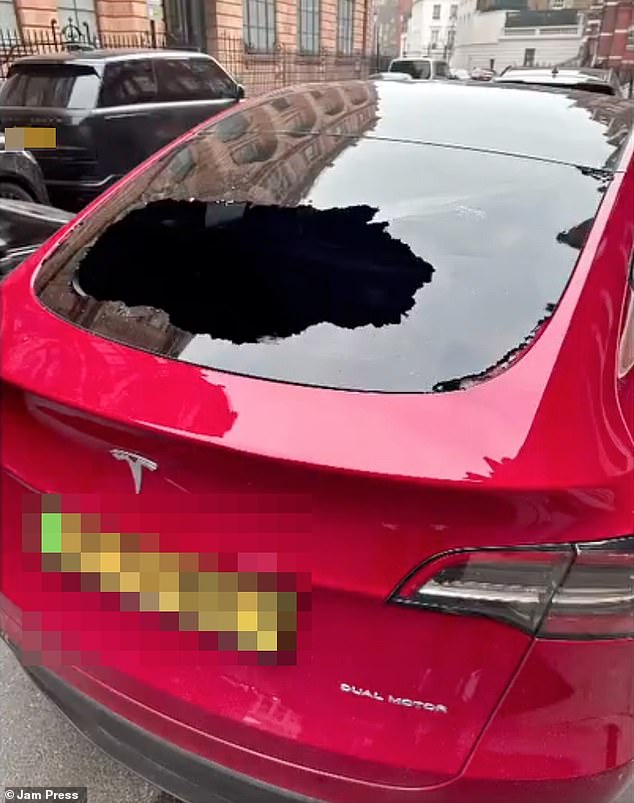 The Tesla is seen with a smashed window after a cyclist broke in to steal a £1,000 Stone Island jacket