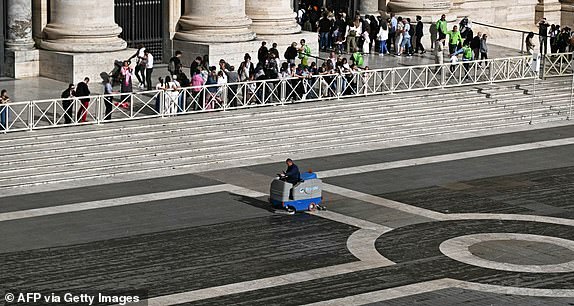A worker (C) drives a cleaning machine on St Peter's Square with the statue of Saint Peter (Bottom C) ahead of the second voting session of the conclave in the Vatican on May 8, 2025. (Photo by Gabriel BOUYS / AFP) (Photo by GABRIEL BOUYS/AFP via Getty Images)