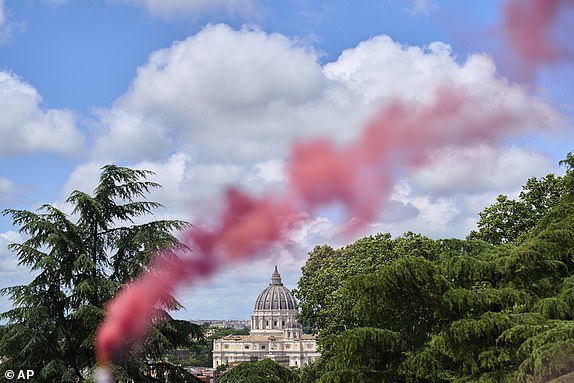 Pink smoke rises in front of St. Peter's Dome during a protest by the Women's Ordination Conference, calling for full equality for women in the Catholic Church on the first day of the conclave to elect the 267th pope, in Rome, Wednesday, May 7, 2025. (AP Photo/Bernat Armangue)
