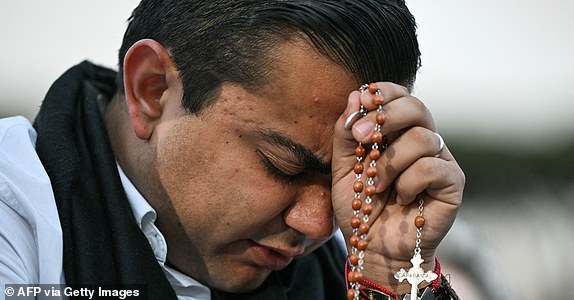 A faithful prays with a rosary as he waits for the smoke to rise from the chimney on the Sistine Chapel as conclave to elect a new Pope starts, at St Peter's Square in The Vatican, on May 7, 2025. (Photo by Stefano Rellandini / AFP) (Photo by STEFANO RELLANDINI/AFP via Getty Images)
