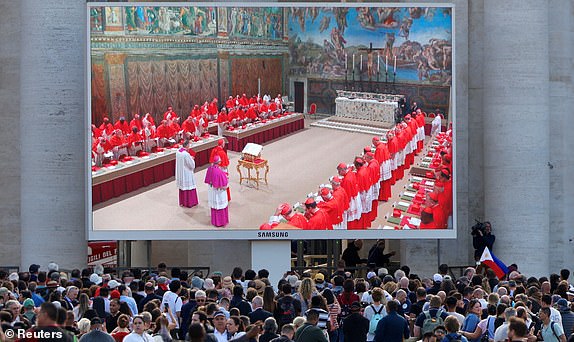 People watch a screen in Saint Peter's Square showing Cardinals in the Sistine Chapel, on the first day of the conclave to elect the next pope, as seen from Rome, Italy, May 7, 2025. REUTERS/Kevin Coombs