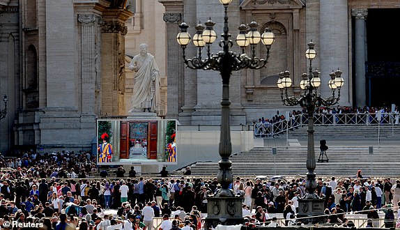 People watch a screen in Saint Peter's Square showing the doors of the Sistine Chapel, on the first day of the conclave to elect the next pope, as seen from Rome, Italy, May 7, 2025. REUTERS/Kevin Coombs