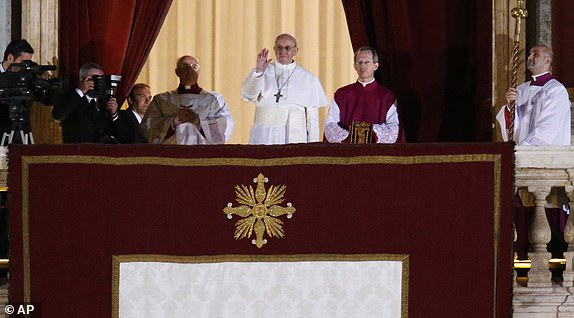 FILE - Pope Francis flanked by Monsignor Guido Marini, master of liturgical ceremonies, waves to the crowd from the central balcony of St. Peter's Basilica at the Vatican, Wednesday, March 13, 2013. (AP Photo/Michael Sohn, File)