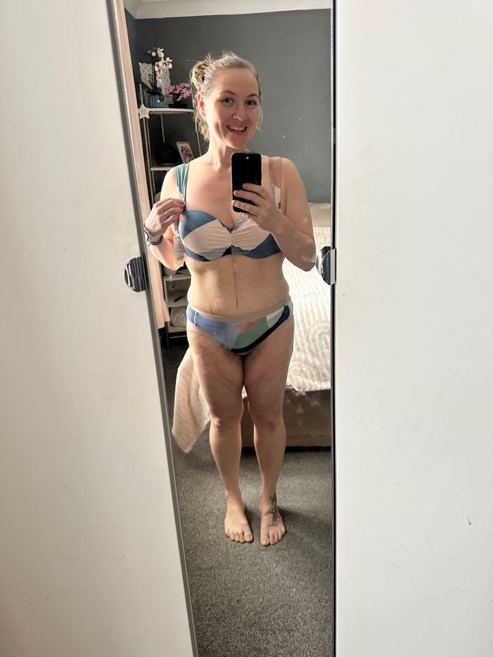 Woman in a swimsuit taking a selfie in a mirror.