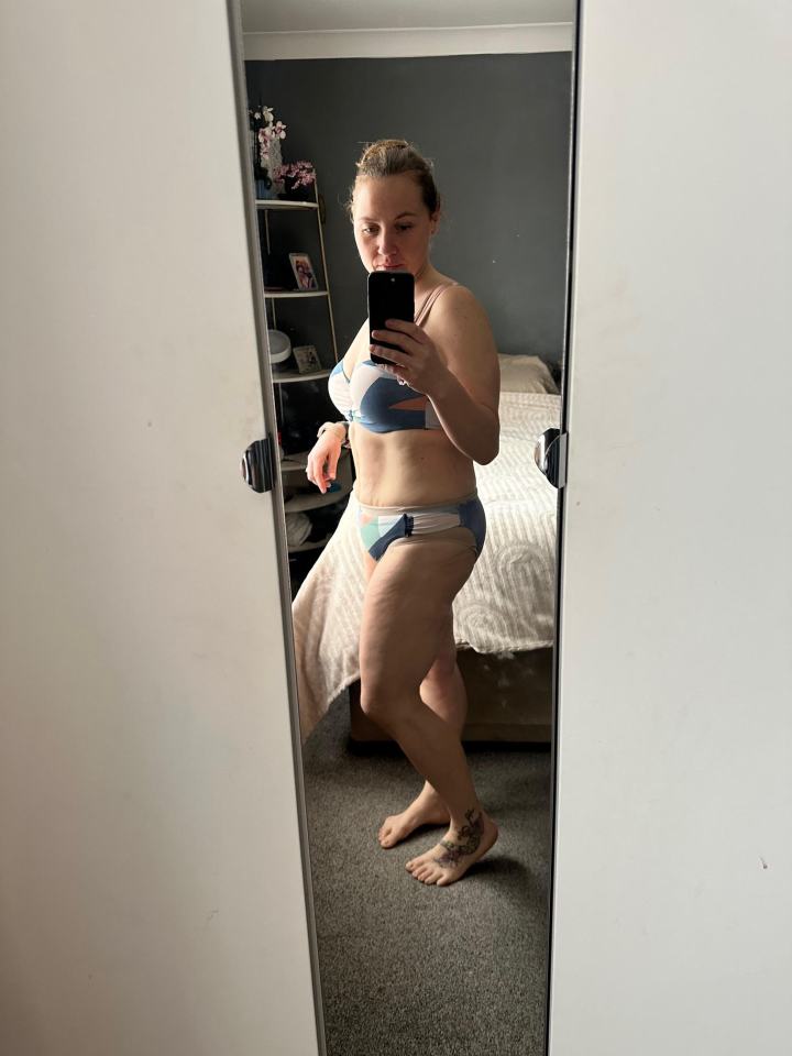 Woman in a swimsuit taking a selfie in a mirror.